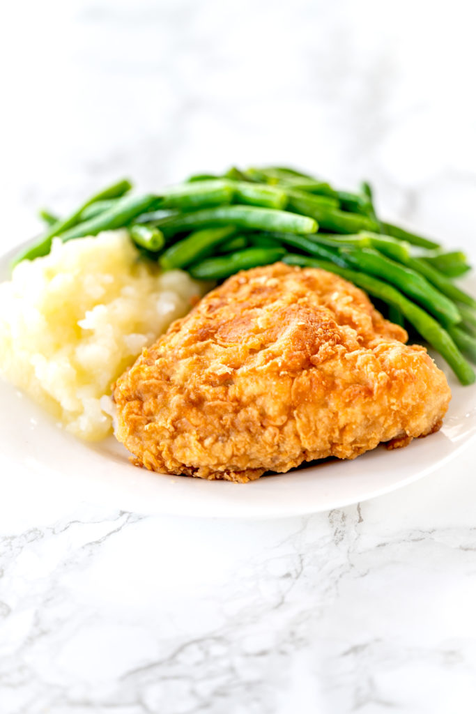 fried chicken made without buttermilk sitting on a plate with mashed potatoes and green beans