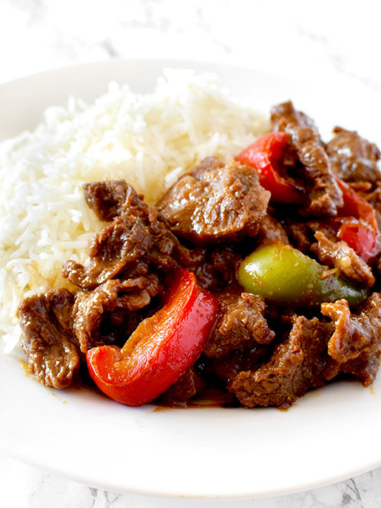 pepper steak and rice on a white plate on a white marble counter