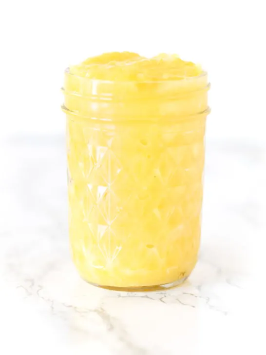 lemon curd in a jar on a white marble counter