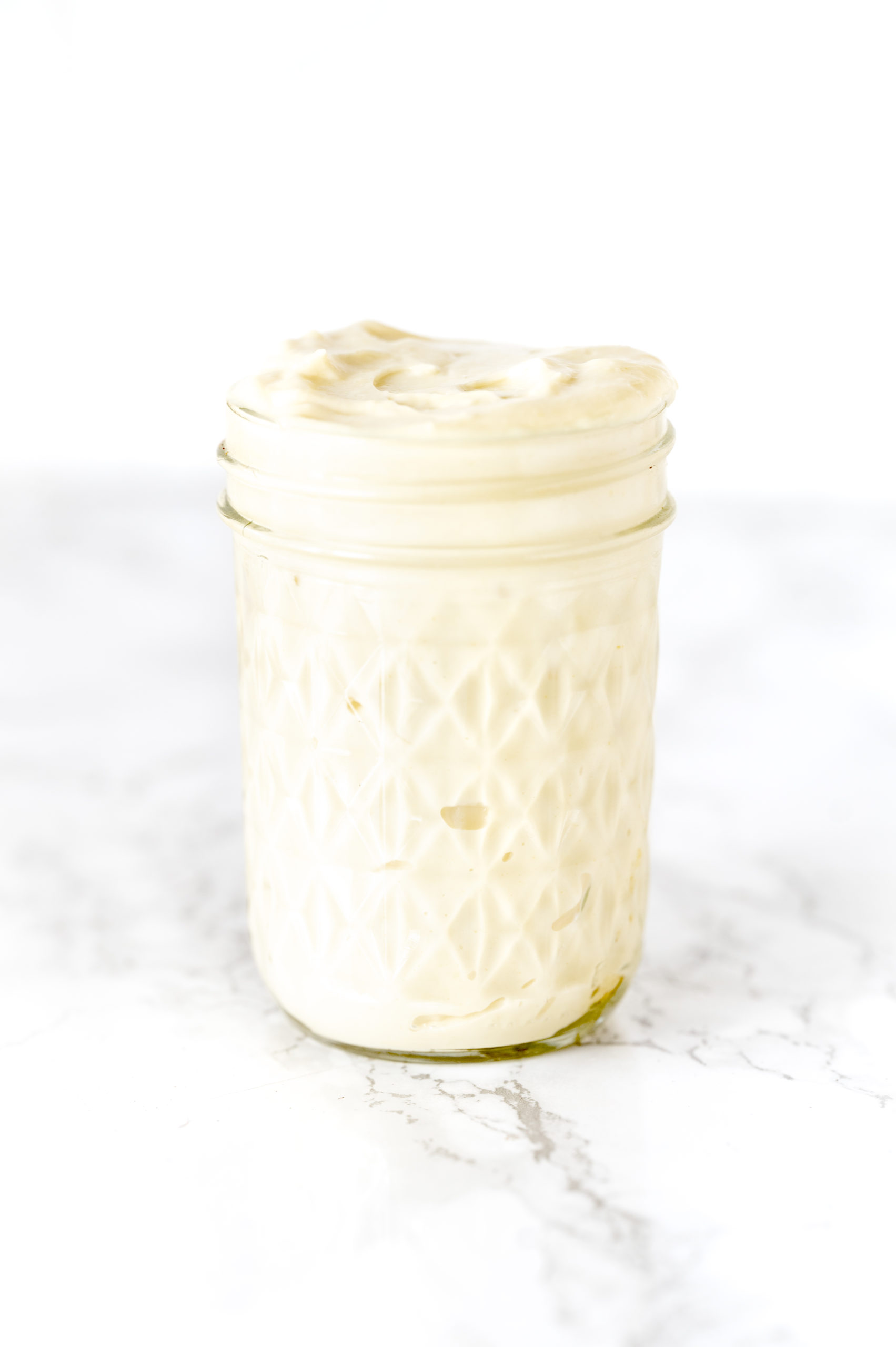 mayonnaise in a glass jar on a white marble counter