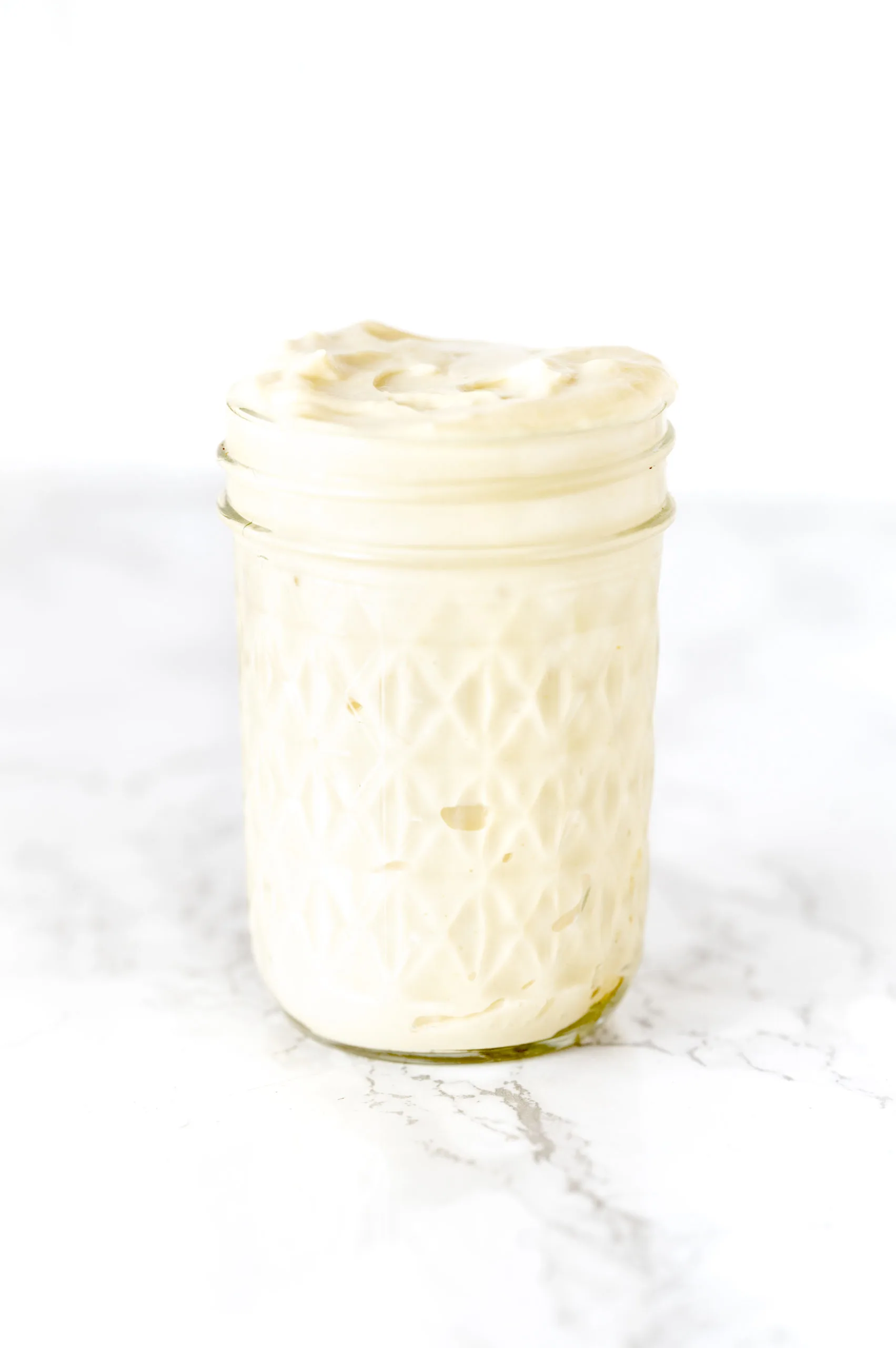 mayonnaise in a glass jar on a white marble counter