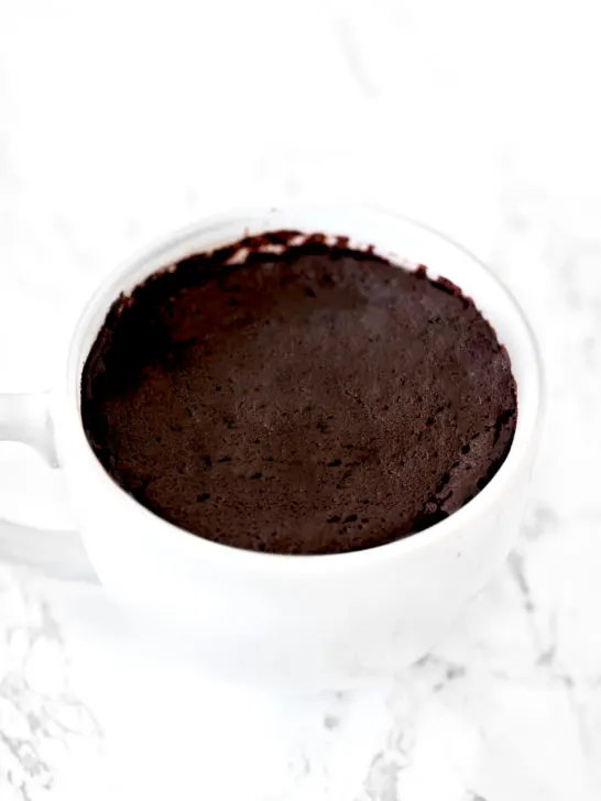 chocolate mug cake in a white mug on a white marble counter