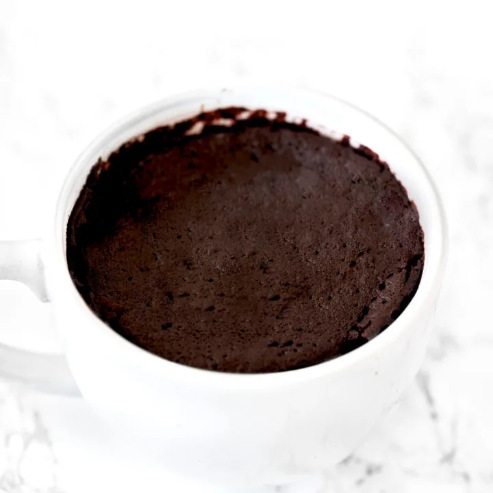 chocolate mug cake in a white mug on a white marble counter