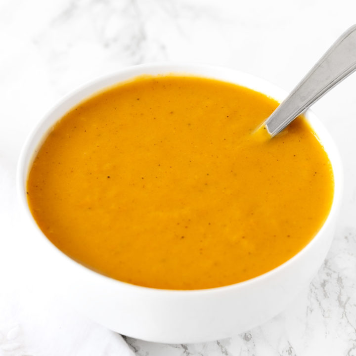 dairy free butternut squash soup in a white bowl on a white marble counter