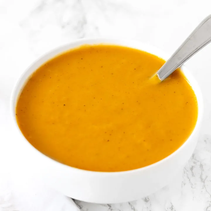 dairy free butternut squash soup in a white bowl on a white marble counter