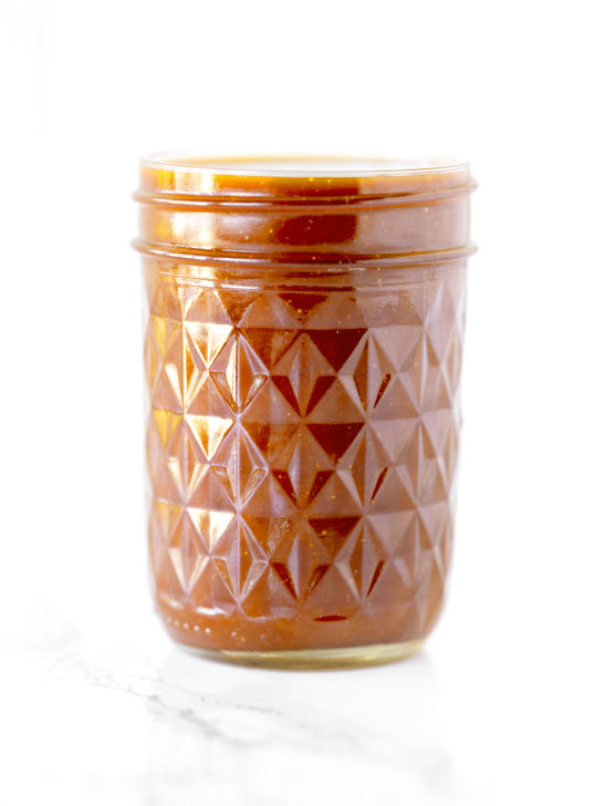 dairy free caramel in a glass jar on a white marble counter