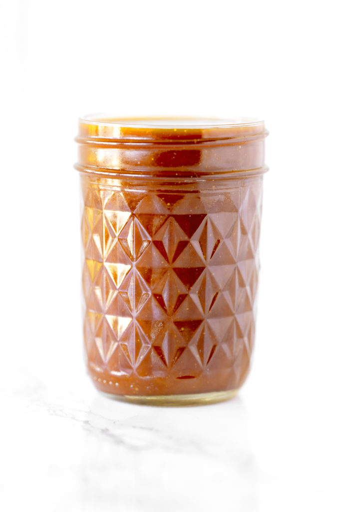 dairy free caramel in a glass jar on a white marble counter