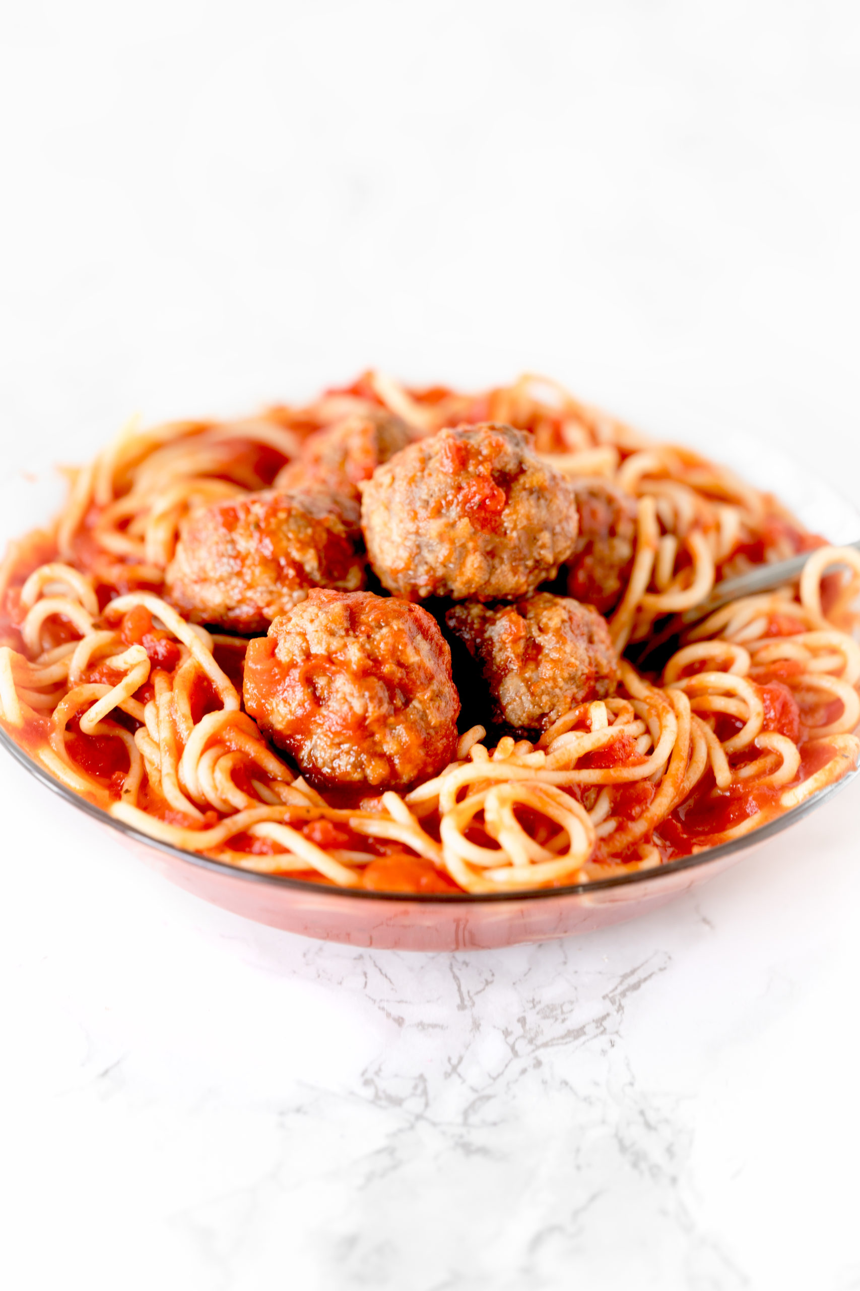 gluten free dairy free meatballs in a bowl of spaghetti on a white marble counter