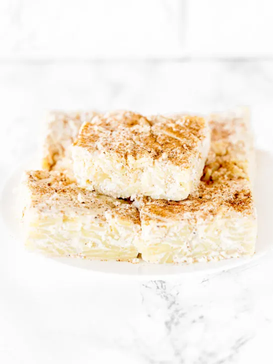 Noodle kugel on a white plate on a white marble counter