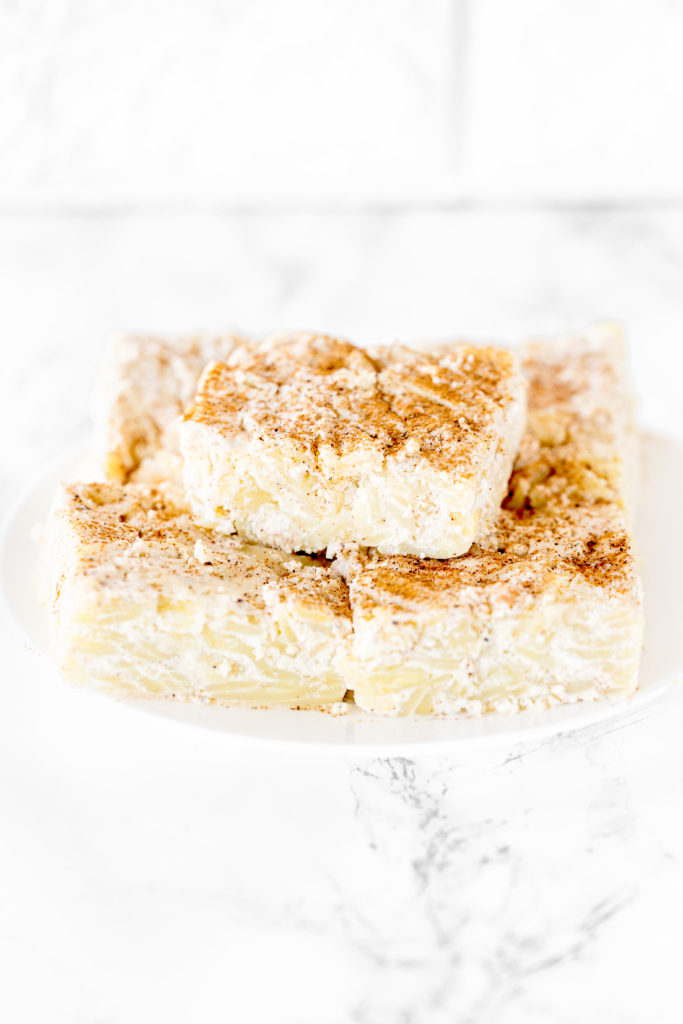 Noodle kugel on a white plate on a white marble counter