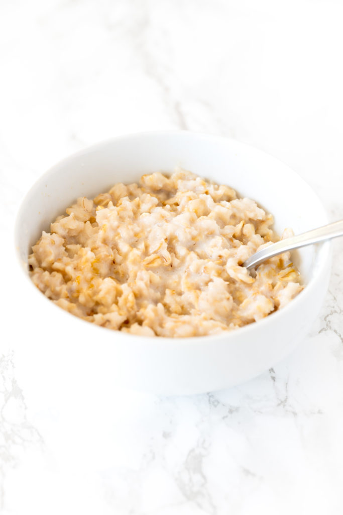 oatmeal with coconut milk in a white bowl on a white marble counter