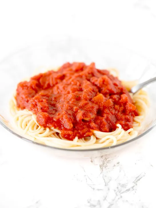 dairy free pasta sauce on a bowl of spaghetti on a white marble counter