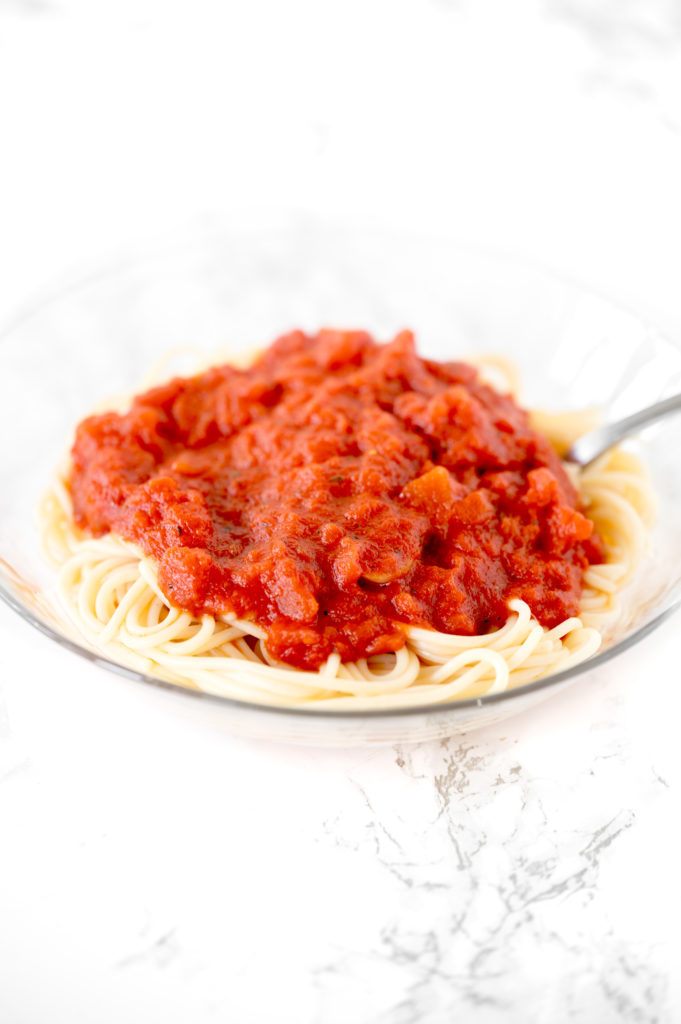 dairy free pasta sauce on a bowl of spaghetti on a white marble counter