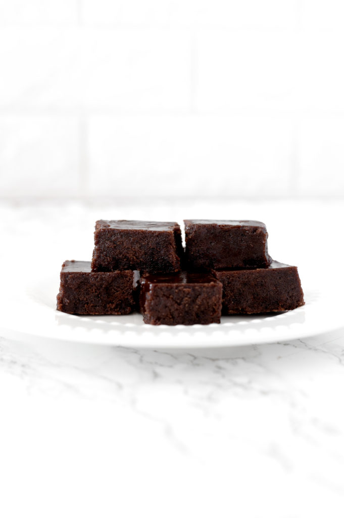 dairy free fudge pieces piled on a white plate on a white marble counter