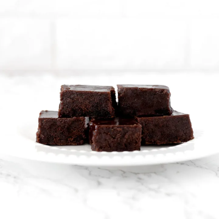 dairy free fudge pieces piled on a white plate on a white marble counter